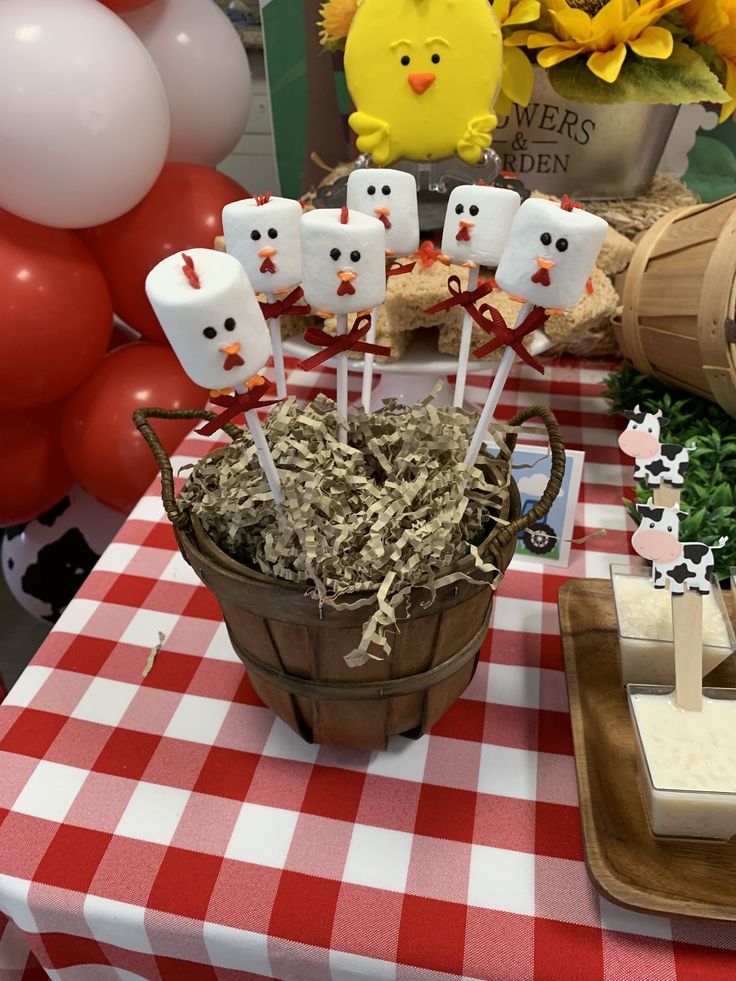 a table topped with marshmallows and cake pops on top of a red checkered table cloth