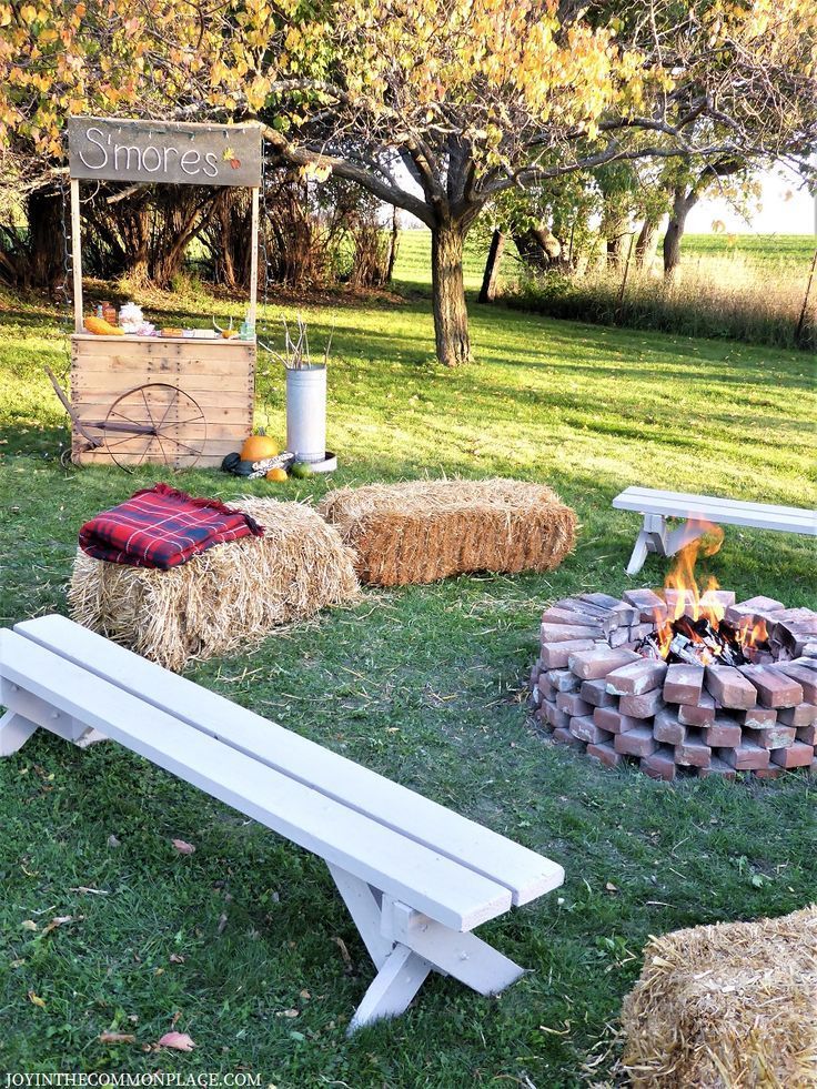 a fire pit with hay bales around it and a picnic table in the background