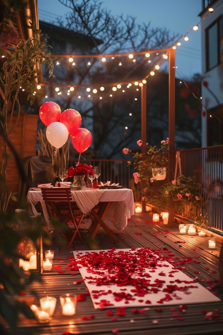 a table with candles and balloons on it in the middle of a deck at night