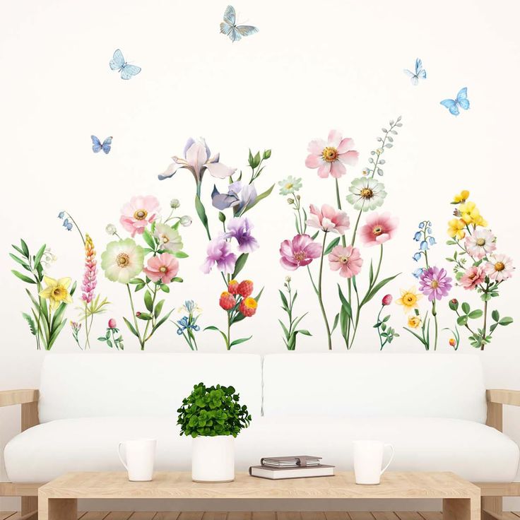 a living room with flowers and butterflies painted on it's wall behind a white couch