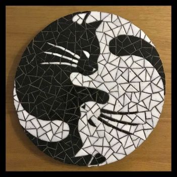 a black and white mosaic tile with a cat kissing on it's face in front of a wooden table