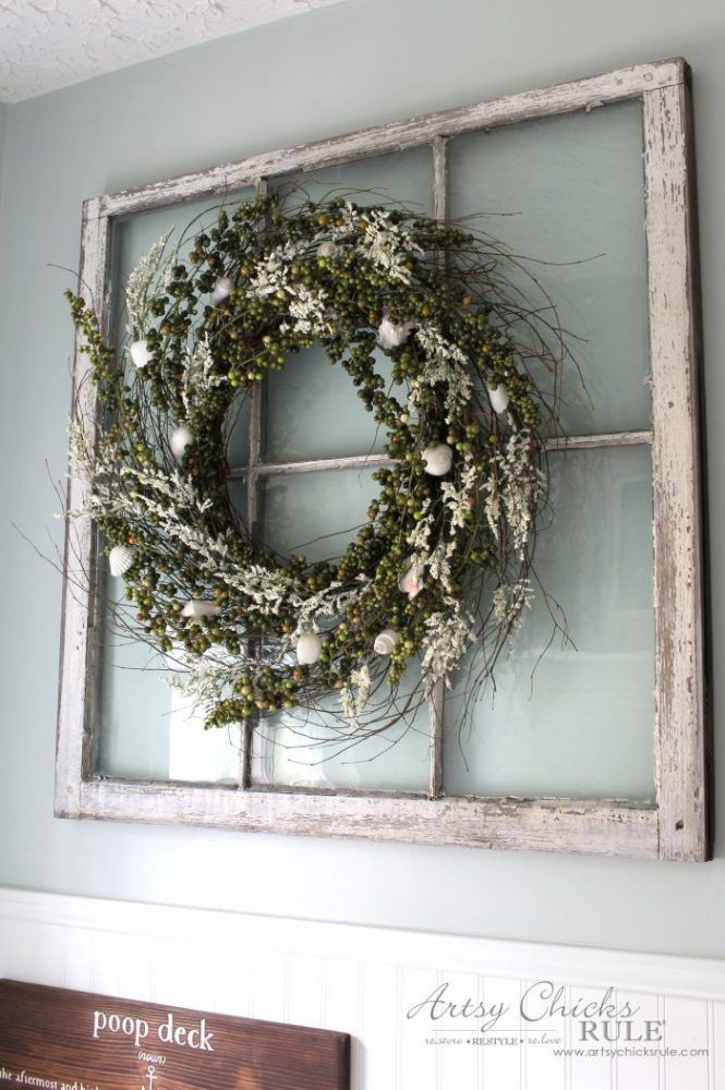 an old window frame is decorated with greenery and a wreath for the front door