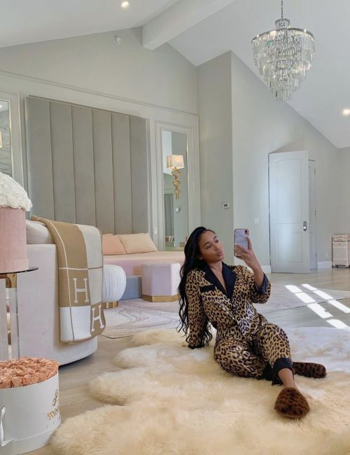 a woman sitting on the floor taking a selfie with her phone in a bedroom