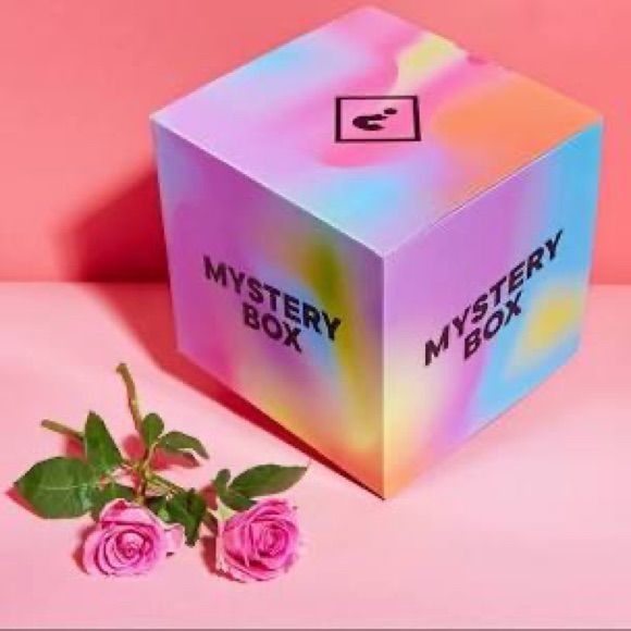 the mystery box is next to two pink roses on a pink surface with a pink background