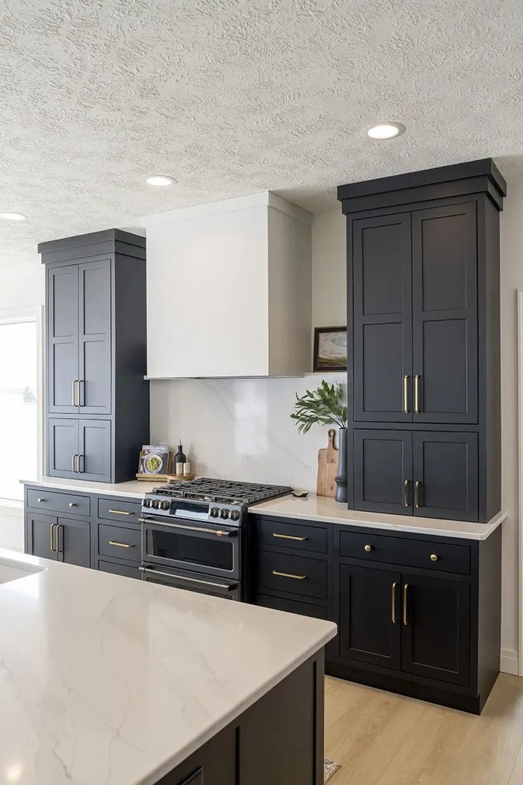 a large kitchen with black cabinets and white counter tops, along with an island in the middle