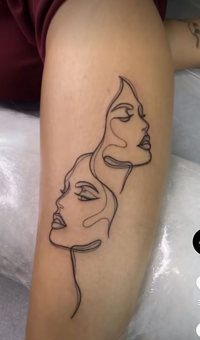 a woman's leg with a line drawing of two faces on it, and the other side of her arm