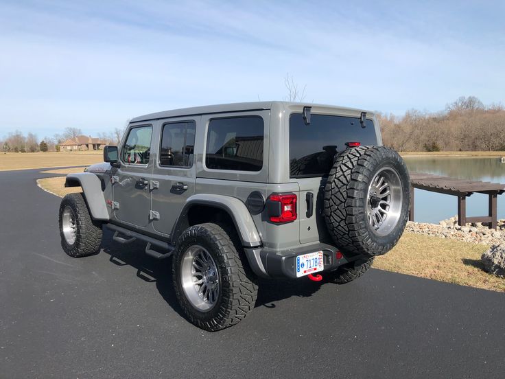 a gray jeep parked on the side of a road next to a body of water