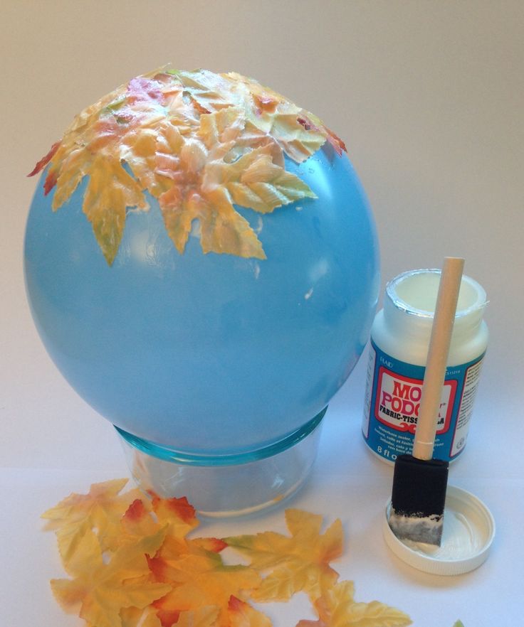 a blue vase sitting on top of a table next to some paint and paper flowers