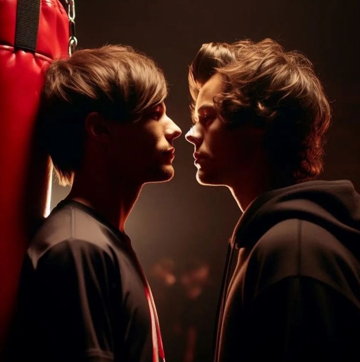 two young men standing next to each other in front of a red boxing punching bag