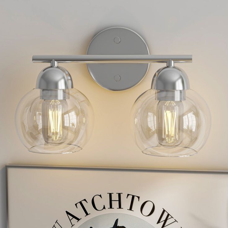 two light bathroom fixture with clear glass shades on the wall and below it's logo