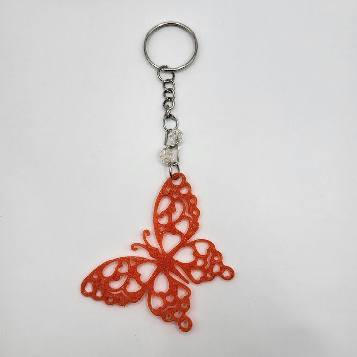 an orange butterfly shaped key chain on a white background