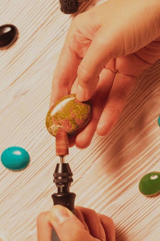 two people are working on something in the middle of a table with other objects around them