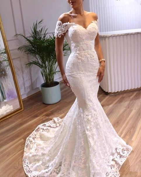 a woman in a white wedding dress standing on a wooden floor next to a mirror