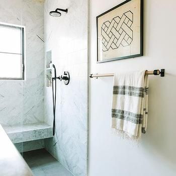 a bathroom with white walls and marble flooring, towel rack on the wall next to the shower