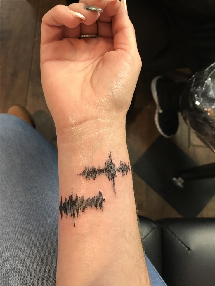 a woman's wrist with a sound wave tattoo on it