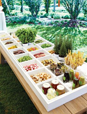 a picnic table with food and drinks on it in the middle of a grassy area