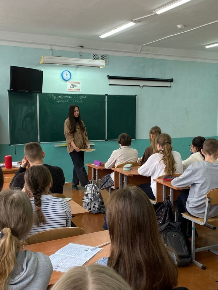 a group of people sitting at desks in front of a blackboard