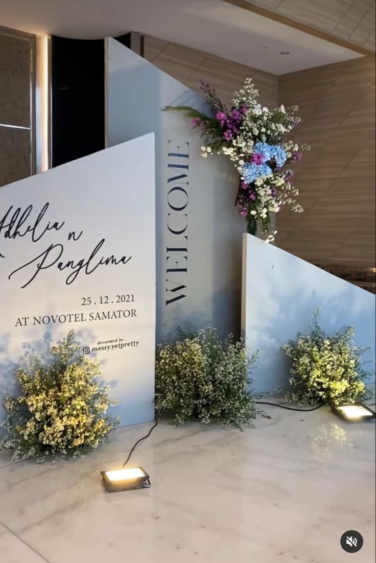 flowers and candles are placed on the table in front of a sign for an event