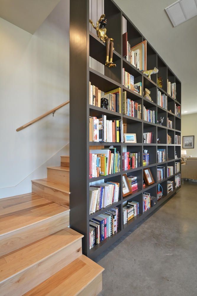 a bookshelf filled with lots of books next to stairs