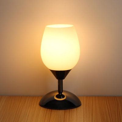 a white light sitting on top of a wooden table next to a black lamp shade