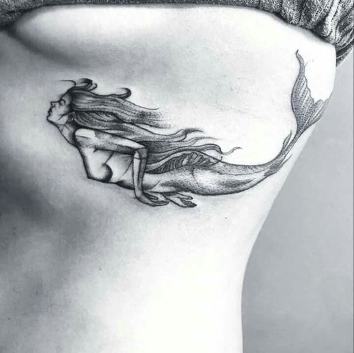 a woman's stomach with a mermaid tattoo on her belly and the bottom part of her lower back