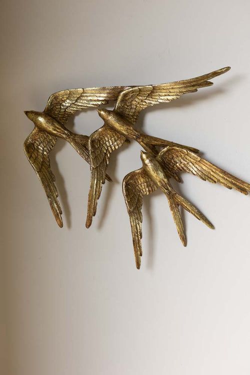 three gold birds are hanging on the wall