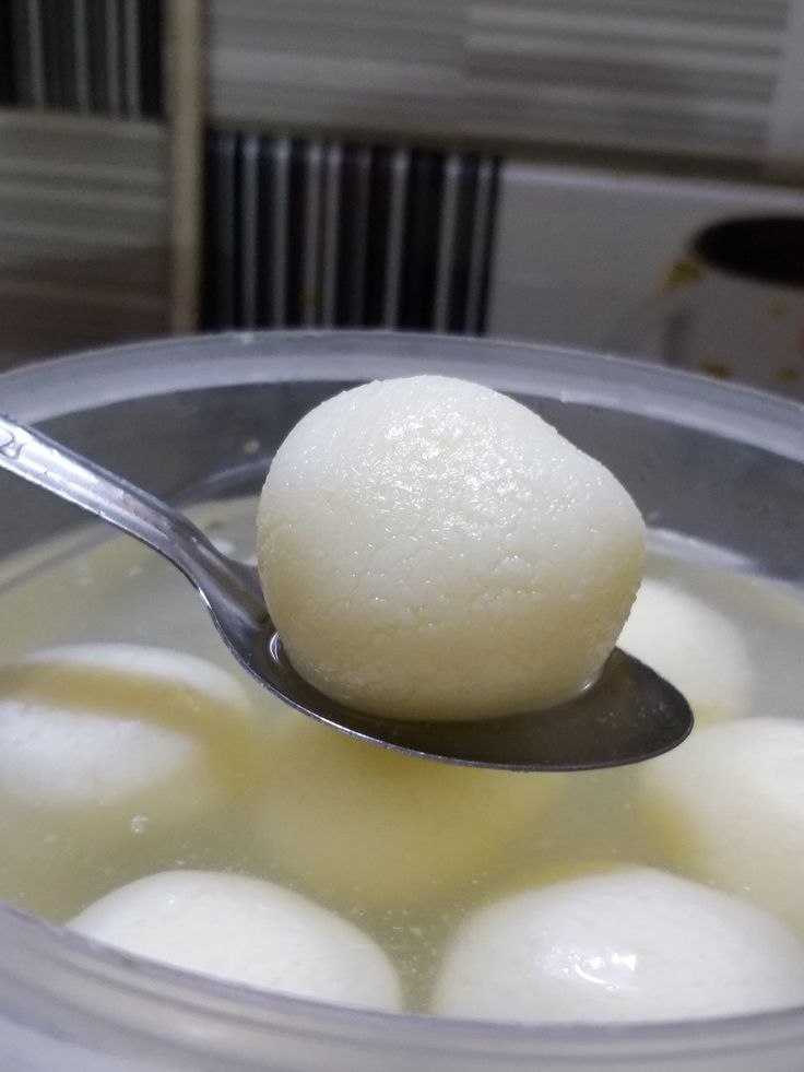 a spoon with some food in it on top of a bowl filled with water and ice cream