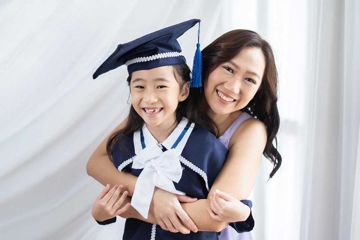 two girls in graduation gowns hugging each other