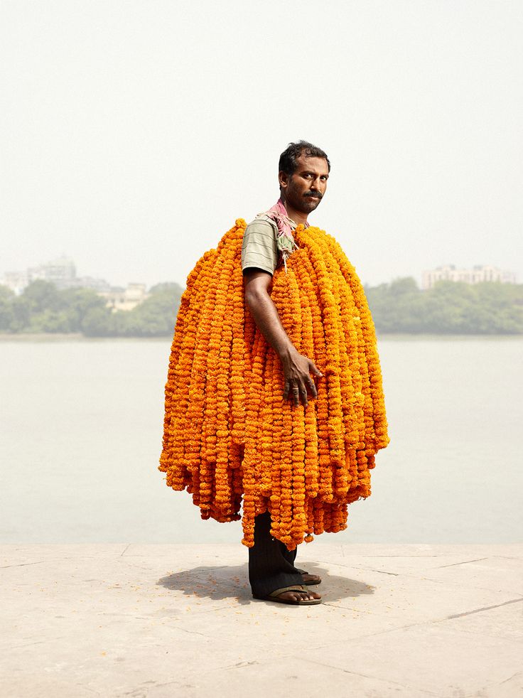 a man standing in front of a body of water holding a large piece of yellow material