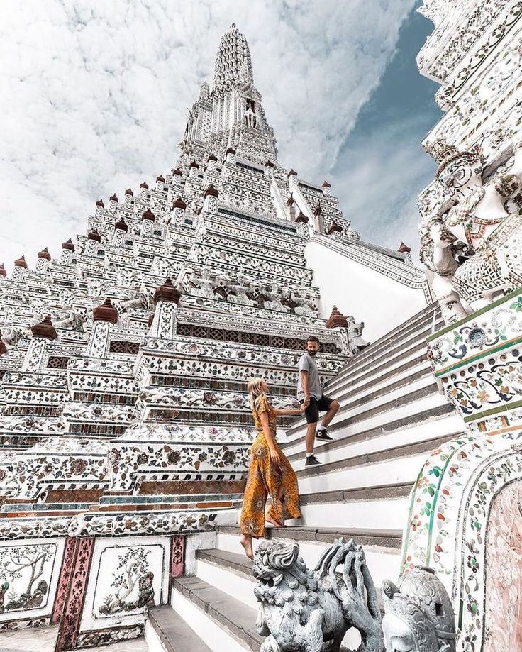 two people are walking up some stairs in front of a building with intricate designs on it