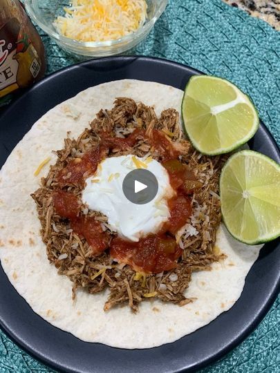 a tortilla topped with shredded meat, sour cream and salsa on a blue plate