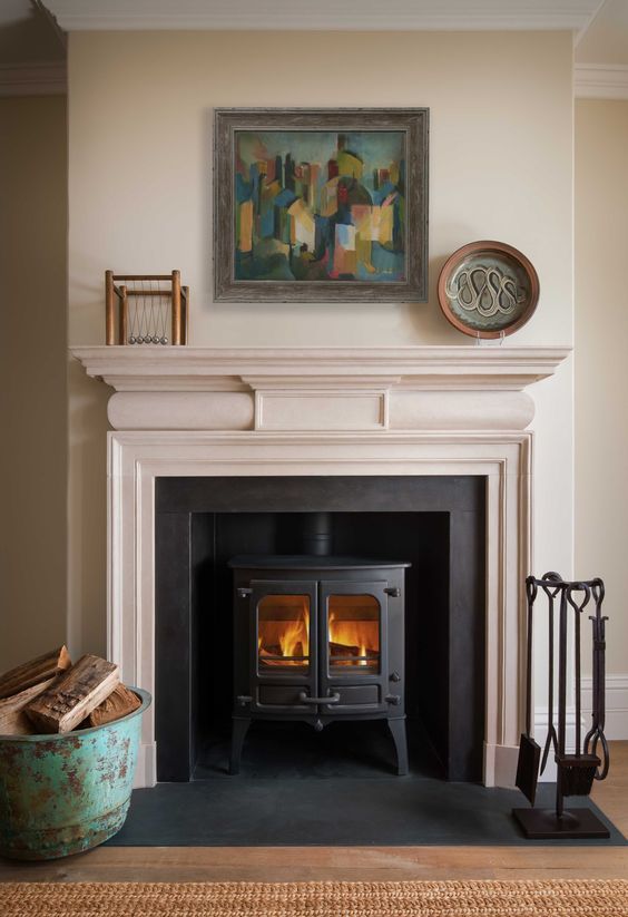 a fire place in a living room with a painting on the wall above it and a basket next to it