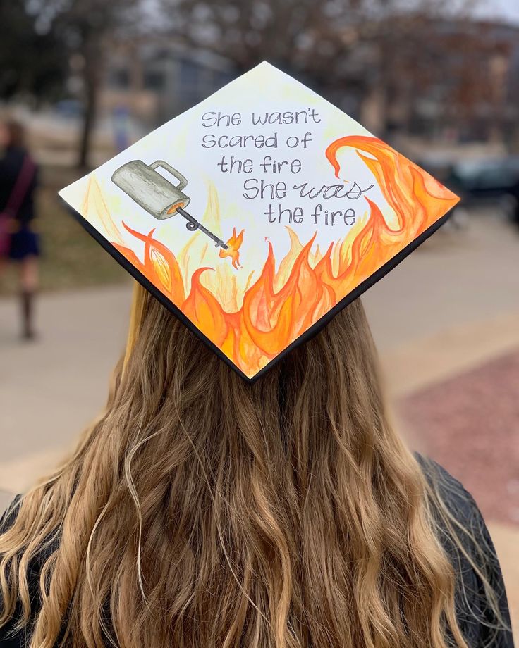 a woman with long hair wearing a graduation cap that reads, and want't scared of the fire she eats the fryer