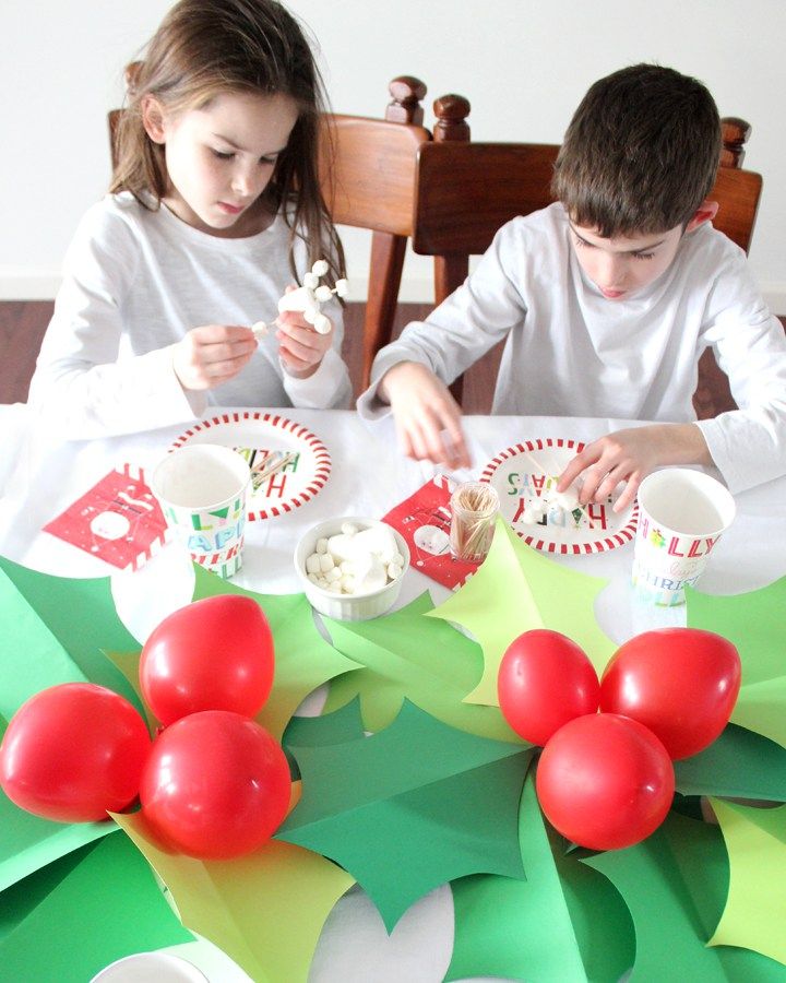 two children sitting at a table with plates and cups on it, decorated for christmas