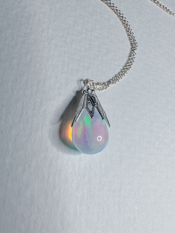 The most dazzling blue multi flash opal raindrop on sterling silver chain and clasp with a silver plate whimsically vintage style beadcap topper 18” Iridescent Teardrop Gemstone Jewelry, Sterling Silver Cabochon Drop Jewelry, Silver Teardrop Gemstone Crystal Necklace, Elegant Iridescent Drop Jewelry, Bohemian Sterling Silver Teardrop Pendant Necklace, Handmade Silver Teardrop Necklaces, Handmade Silver Teardrop Necklace, Spiritual Silver Teardrop Crystal Necklace, Enchanting Silver Necklace