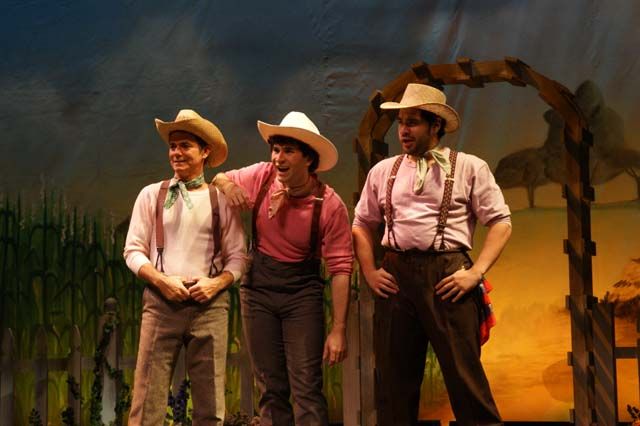 three men in cowboy hats standing on stage with one man looking at the camera and smiling