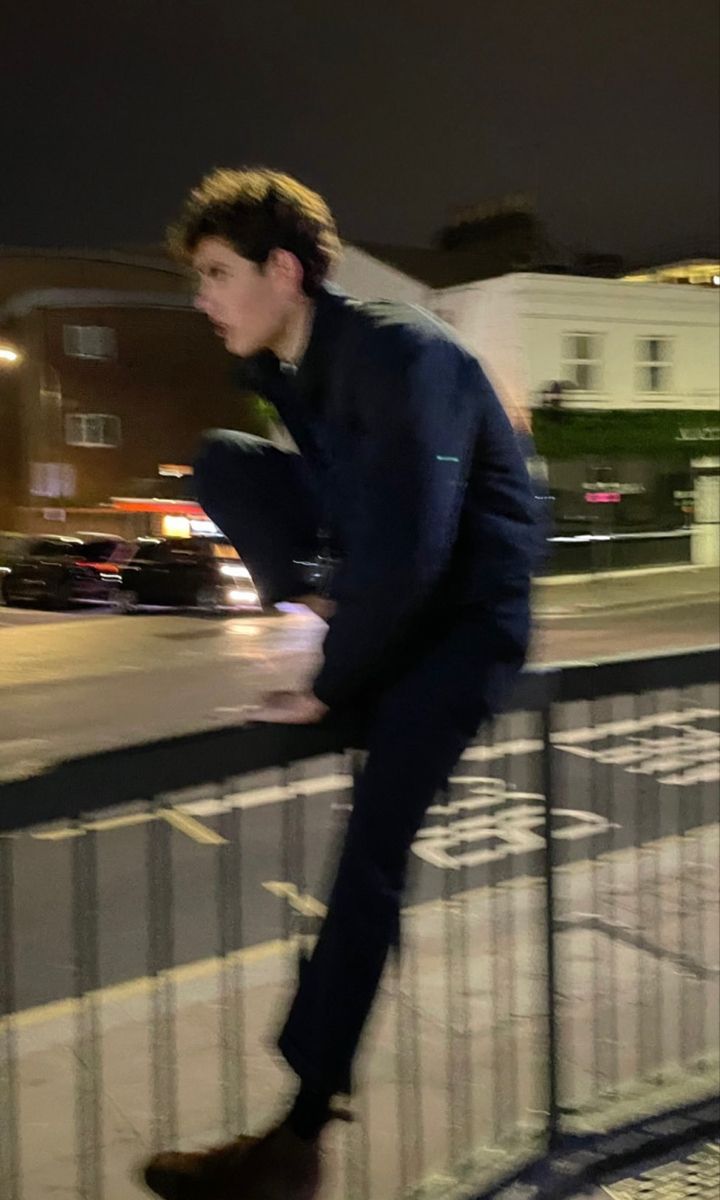 a man in a blue suit is riding a skateboard on a railing near the street