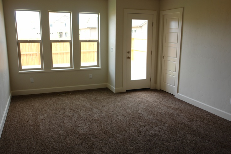 an empty room with three windows and carpet