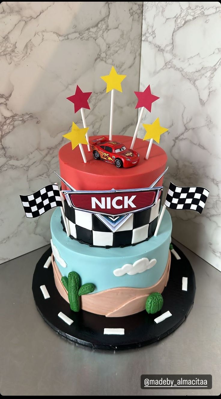 a three tiered cake with cars and stars on top is decorated like a race track