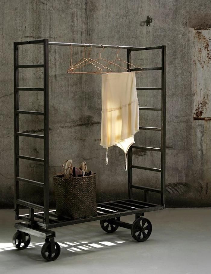 an iron rack with clothes hanging on it and a laundry basket in front of it