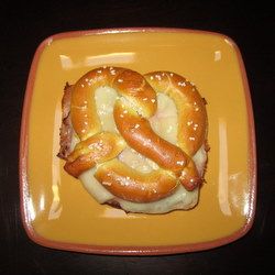 a hot dog on a bun with cheese and ketchup in the shape of a snake