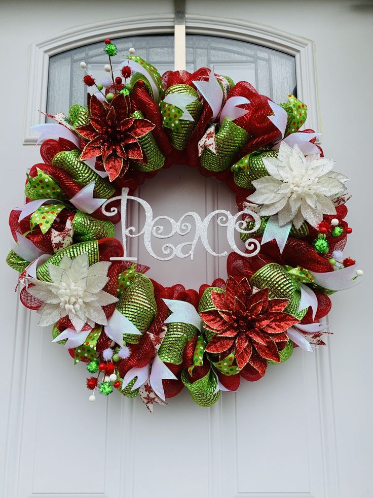 a christmas wreath with poinsettis and ribbons hanging on the front door to say peace