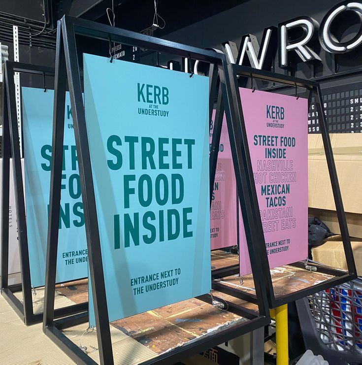 two signs are on display in front of a store window that says street food inside