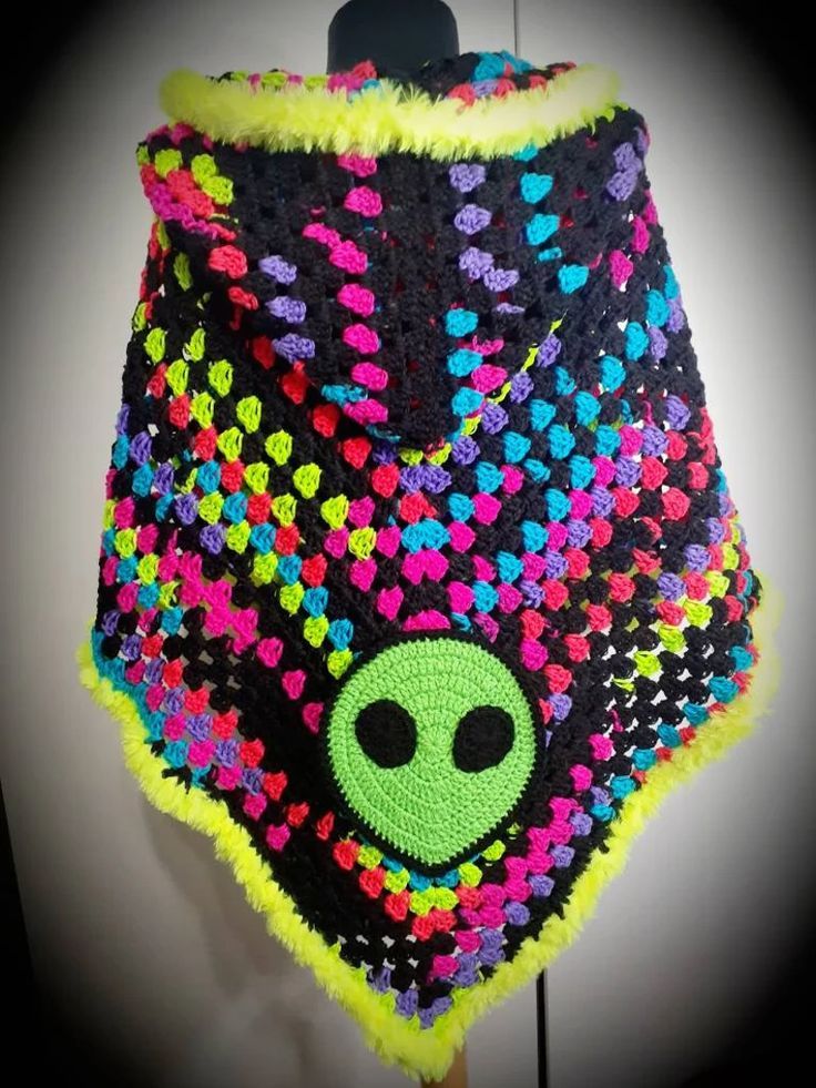 a crocheted alien shawl hanging on a hook