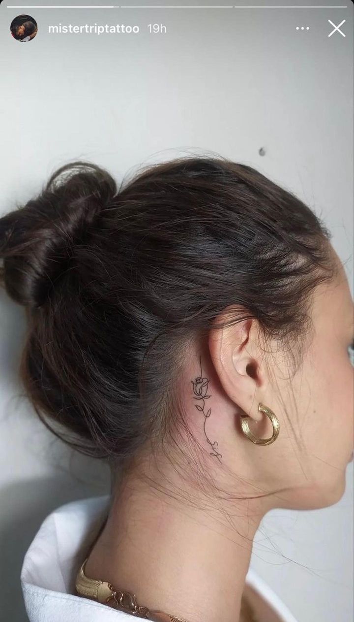 a woman with a tattoo on her neck and behind her ear is looking to the side