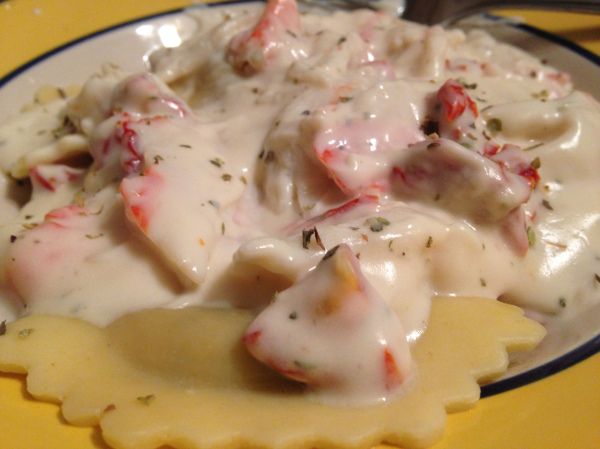 a yellow plate topped with ravioli covered in cheese sauce