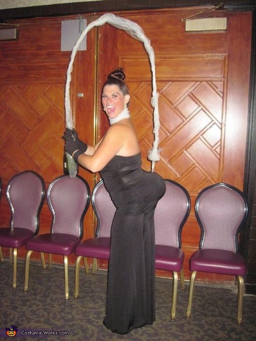 a woman in a black dress standing next to purple chairs