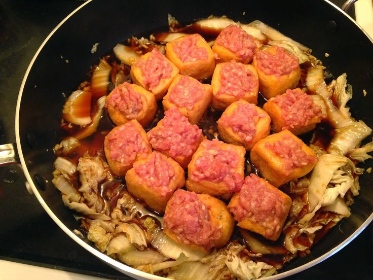 some food is cooking in a skillet on the stove top with meatballs and onions