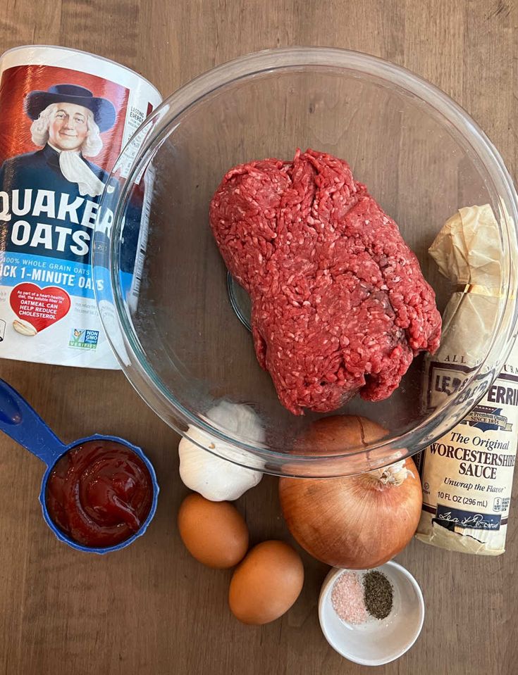 ingredients to make hamburger patties laid out on a wooden counter top, including onions, eggs, mayonnaise and ground beef