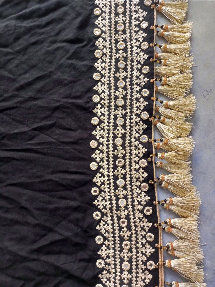 two pieces of cloth with fringes and beads on the edges, one black and one white